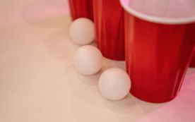 Red Cups Beside Small Balls on a White Surface