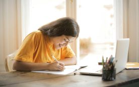 Woman in Yellow Shirt Writing on White Paper